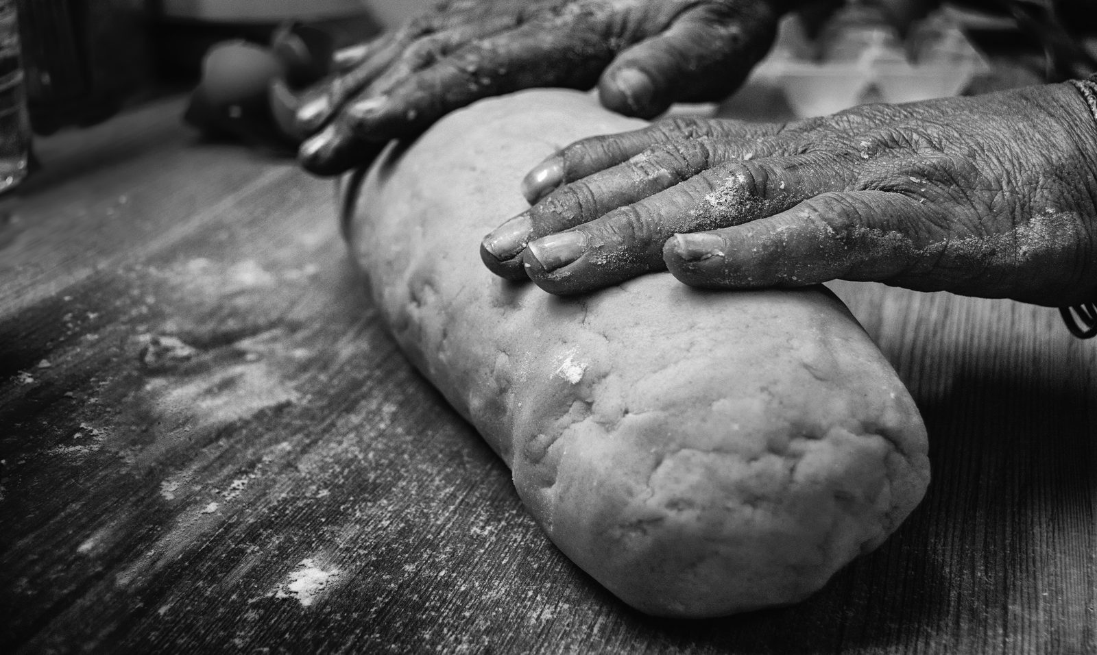 Aged hands kneading dough on a floured surface, black and white