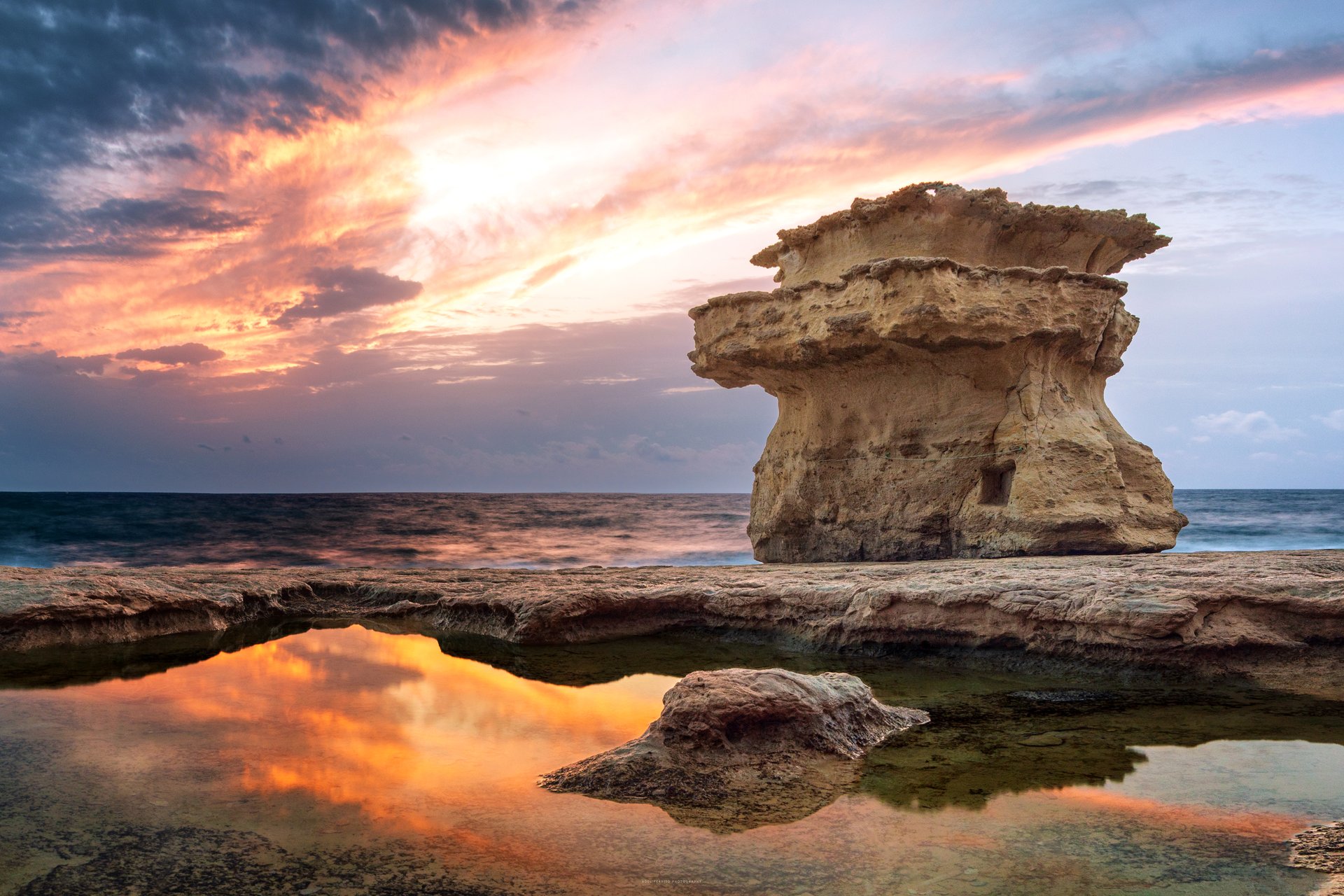 Sunrise over the rock formations and still pool at St Peter's Pool, Malta