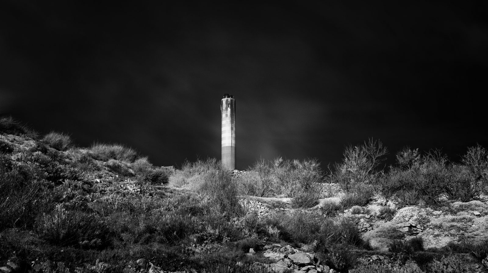 The Delimara power station chimney across the water, seen from St Peter's Pool, infrared black and white