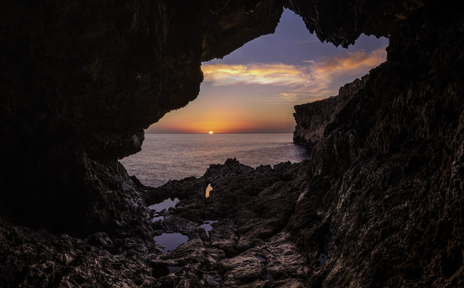 Sunset seen from inside a sea cave at Għar Lapsi, Malta