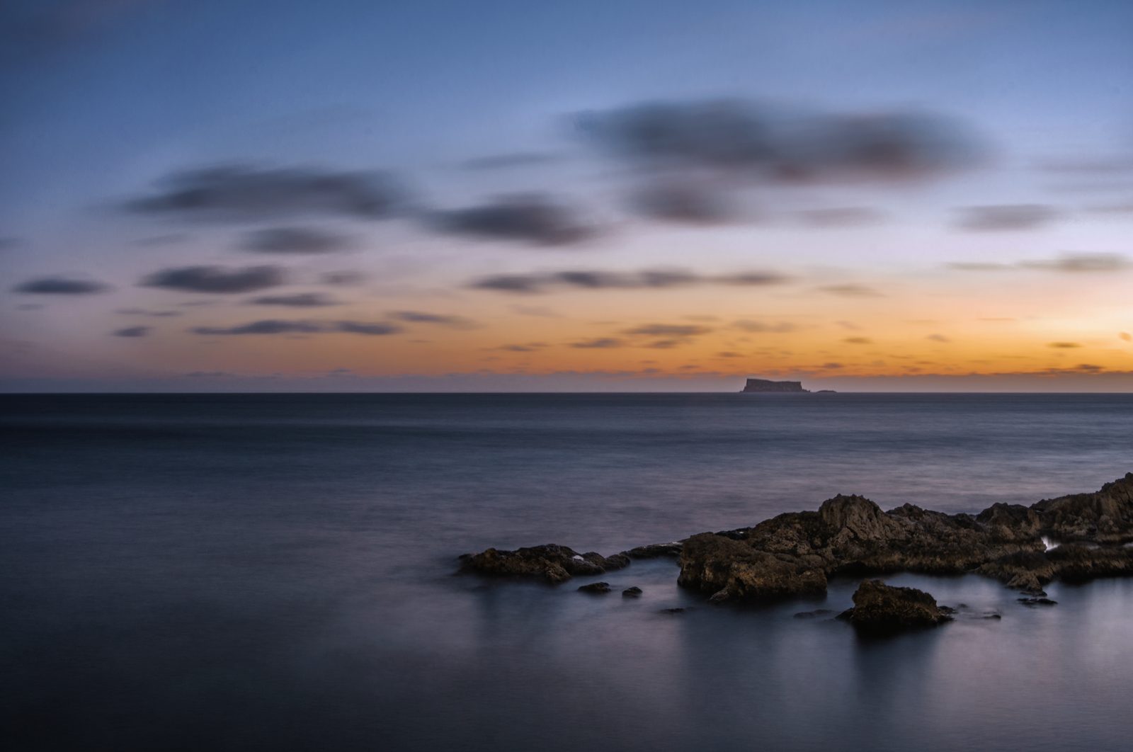 The islet of Filfla on a minimal sunset horizon, seen from Għar Lapsi