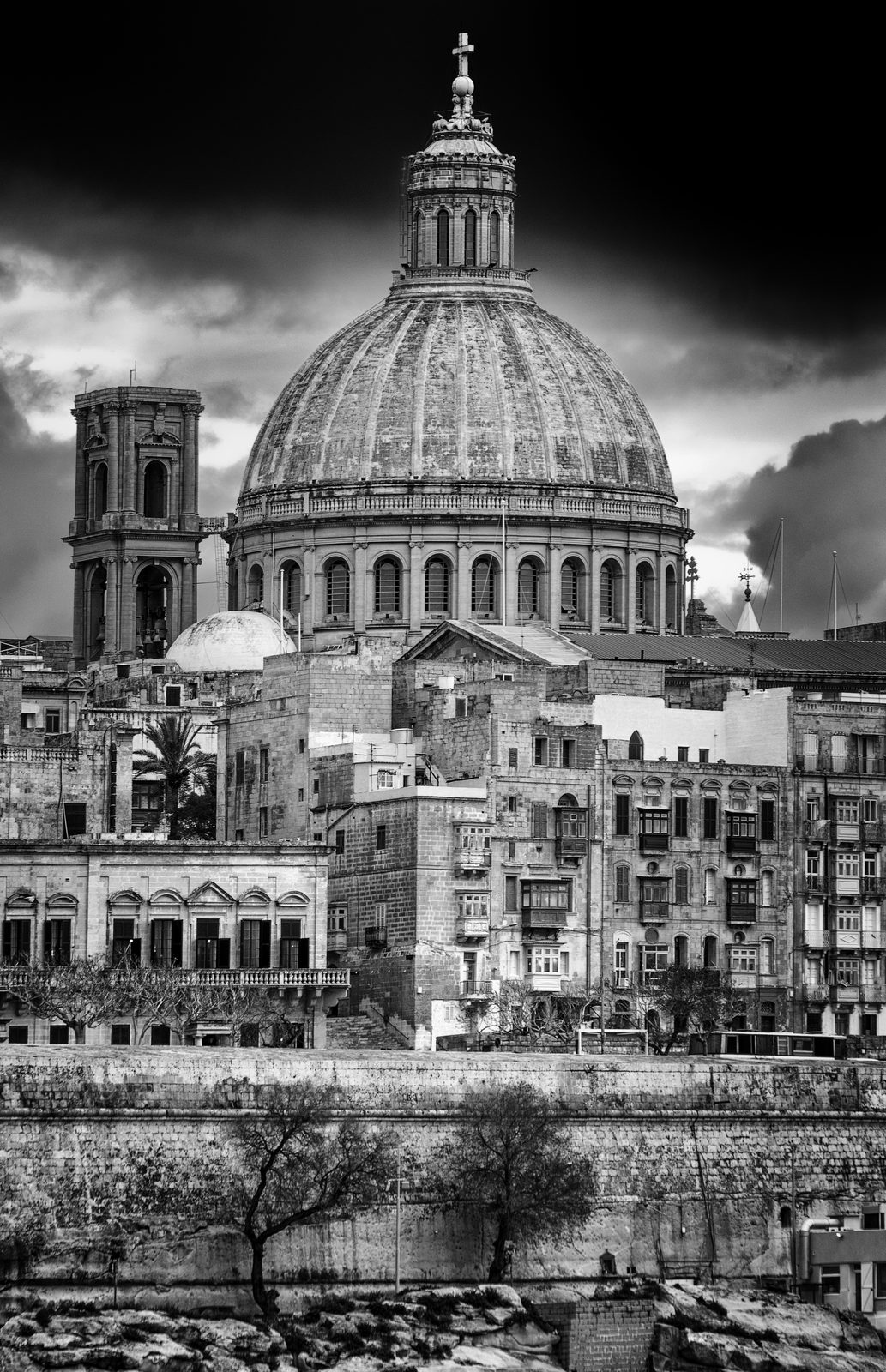 The steeple of the Basilica Sanctuary of Our Lady of Mount Carmel rising over the rooftops of Valletta in black and white