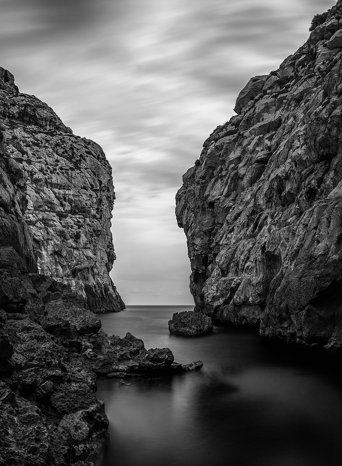 The steep rock walls of Wied Babu valley opening toward the sea, black and white